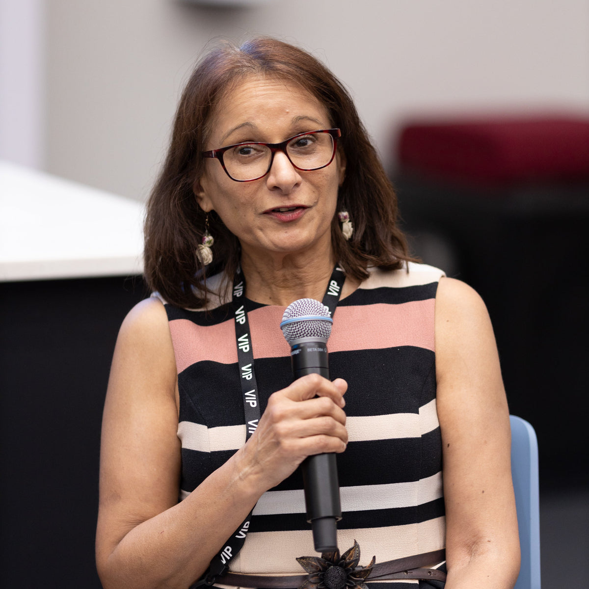 Woman speaking into a microphone at an event with a blurred background
