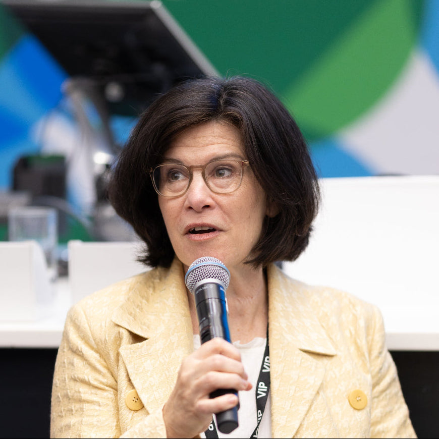 Woman speaking into a microphone at an event with a blurred background